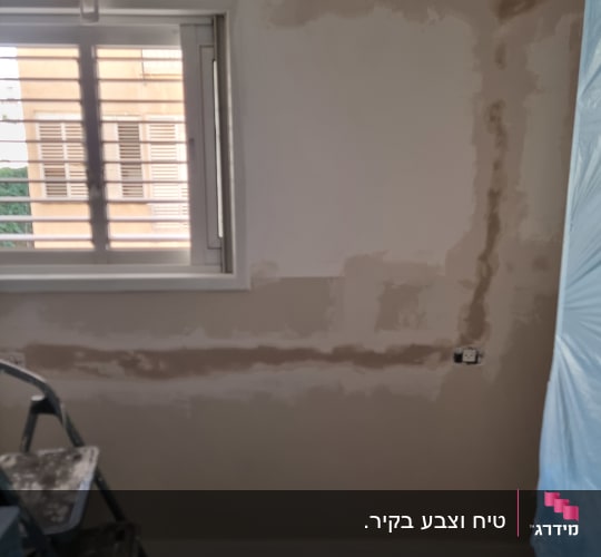 קיר עם תיקוני טיח וסולם בחדר